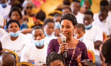 DRC woman speaking into microphone