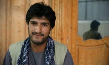 man with scarf and vest smiling at camera